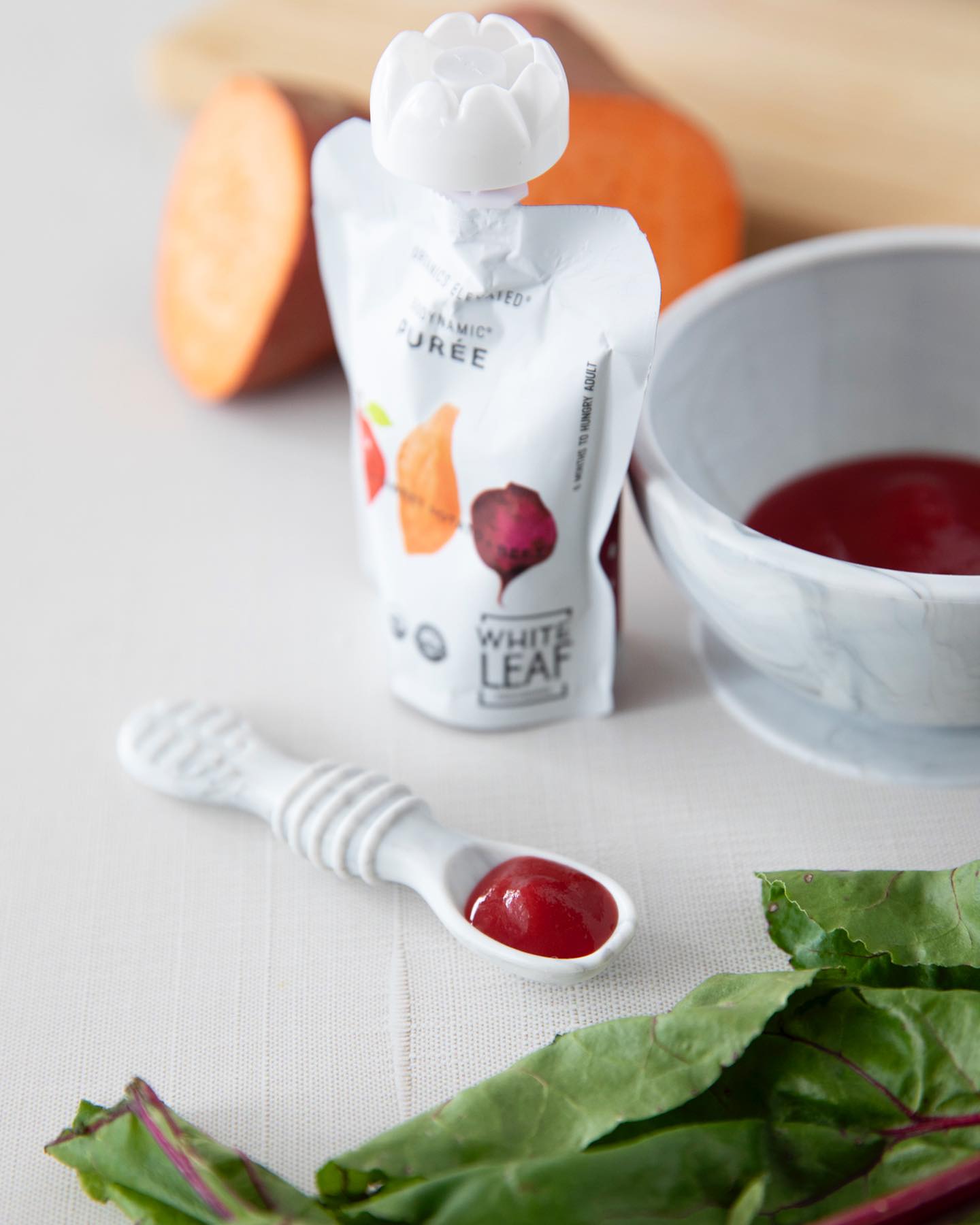spoon holding baby food beet puree from organic food pouch